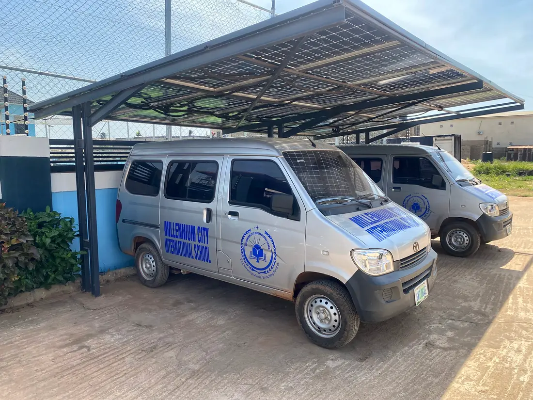 Two branded school buses parked under a solar-panel canopy
