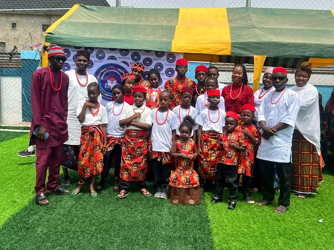 Pupils and teachers in traditional attire under a canopy