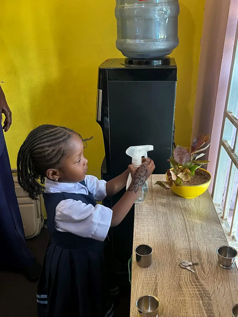 A nursery pupil watering a classroom plant